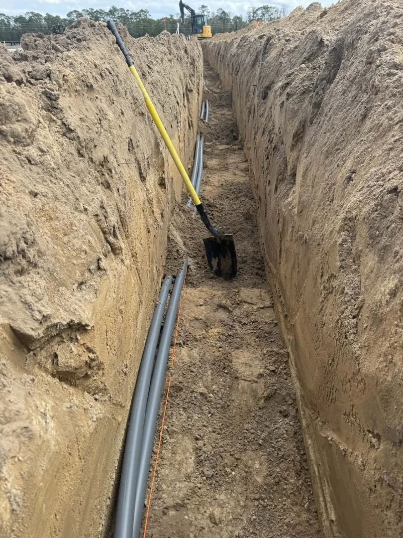Excavator beside a trench with pipe in the ground